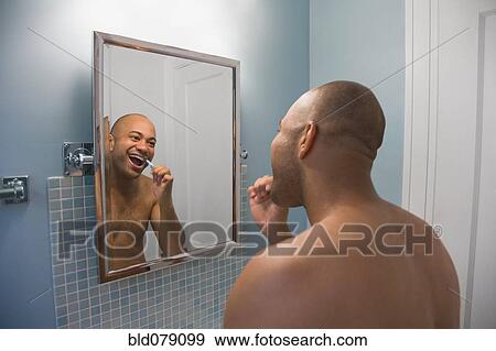 Stock Photo - Mixed race man brushing teeth. Fotosearch