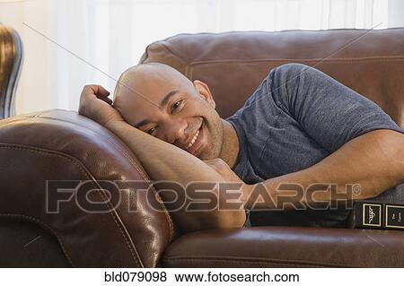 Stock Photo - Mixed race man laying on sofa. Fotosearch