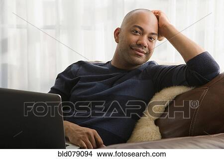 Mixed race man sitting in chair with laptop View Large Photo Image Picture - Mixed race man sitting in chair with laptop. Fotosearch