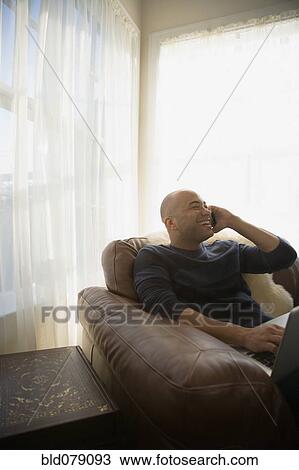 Mixed race man talking on cell phone in living room View Large Photo Image Stock Image - Mixed race man talking on cell phone in living room. Fotosearch