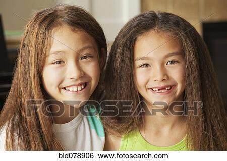 Stock Photograph - Mixed race sisters smiling. Fotosearch