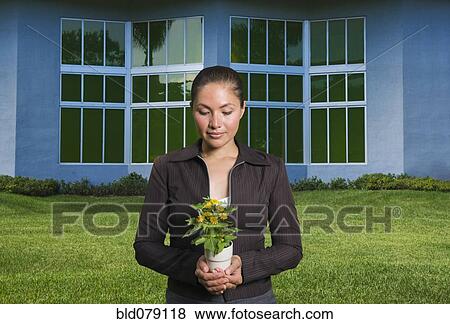 Stock Photo - Mixed race woman holding flowers in pot. Fotosearch