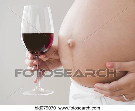 Stock Image - Pregnant Hispanic woman holding glass of wine. Fotosearch