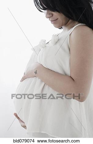Picture - Pregnant Hispanic woman holding stomach. Fotosearch