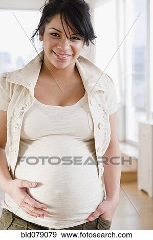 Stock Photo - Pregnant Hispanic woman holding stomach. Fotosearch