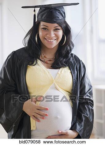 Stock Photo - Pregnant Hispanic woman in graduation cap and gown. Fotosearch