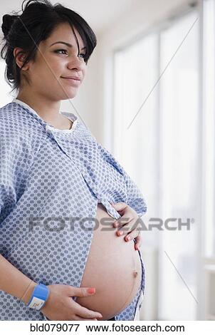Pregnant Hispanic woman in hospital gown View Large Photo Image Stock Photo - Pregnant Hispanic woman in hospital gown. Fotosearch