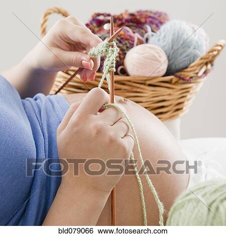 Stock Photograph - Pregnant Hispanic woman knitting with yarn. Fotosearch