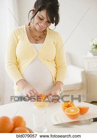 Pregnant Hispanic woman squeezing oranges View Large Photo Image Stock Photo - Pregnant Hispanic woman squeezing oranges. Fotosearch