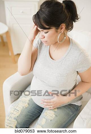 Stock Image - Pregnant Hispanic woman with headache. Fotosearch