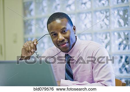 Stock Photograph - African American businessman sitting at desk. Fotosearch