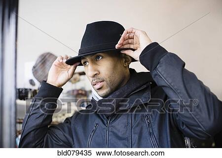 Stock Photography - African American man adjusting fedora. Fotosearch