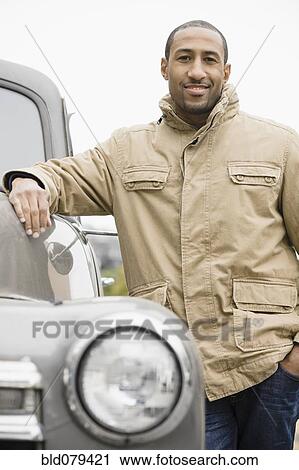 Stock Image - African American man standing next to old-fashioned truck. Fotosearch