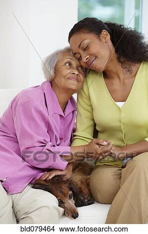 African American woman sitting on sofa with mother and dog View Large Photo Image Picture - African American woman sitting on sofa with mother and dog. Fotosearch