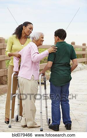 Stock Photograph - African American woman using walker with help of family. Fotosearch