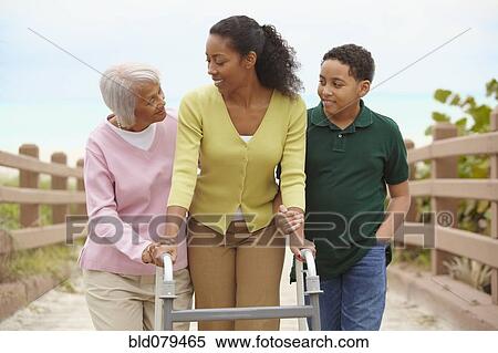 Stock Photography - African American woman using walker with help of family. Fotosearch