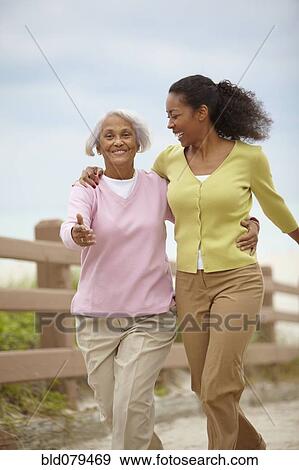 Stock Photo - African American woman walking with mother. Fotosearch