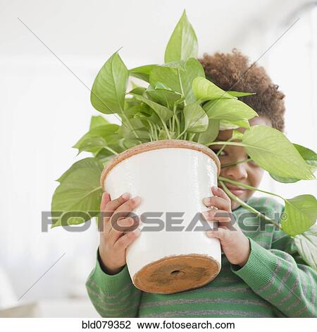 Stock Image - Black boy carrying potted plant. Fotosearch