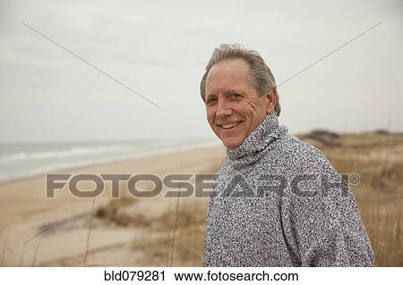 Stock Image - Caucasian man standing on beach. Fotosearch