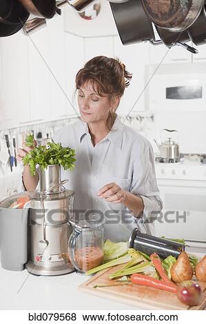 Caucasian woman juicing vegetables in kitchen View Large Photo Image Stock Photo - Caucasian woman juicing vegetables in kitchen. Fotosearch
