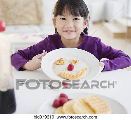 Stock Photo - Chinese girl making a face on plate with waffle. Fotosearch