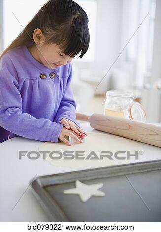 Stock Image - Chinese girl making star-shaped cookies. Fotosearch