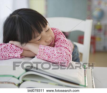Stock Image - Chinese girl napping on textbooks. Fotosearch