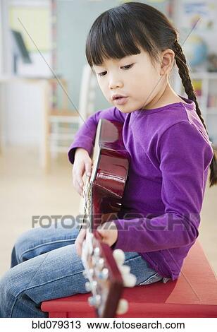Stock Image - Chinese girl playing guitar. Fotosearch
