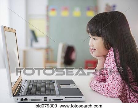 Stock Photo - Chinese girl using laptop in classroom. Fotosearch