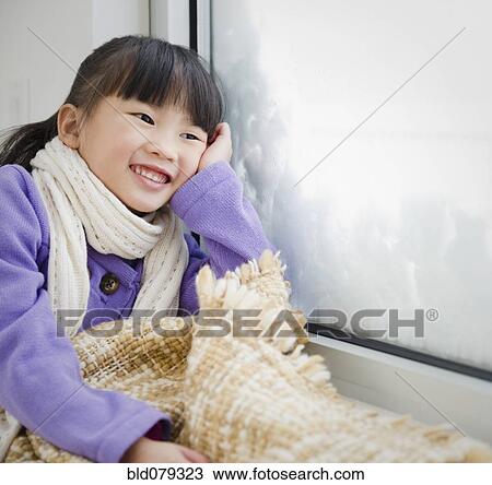 Stock Image - Chinese girl with blanket looking out window. Fotosearch