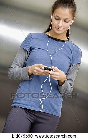 Stock Image - Hispanic woman listening to music on mp3 player. Fotosearch