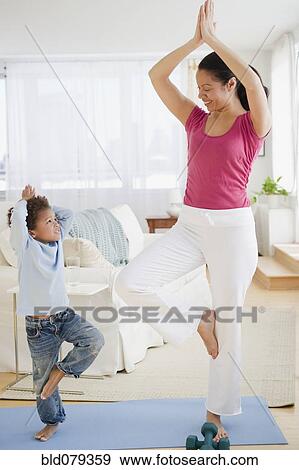 Stock Photo - Mixed race mother and son practicing yoga. Fotosearch