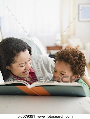 Stock Image - Mixed race mother reading book to son. Fotosearch