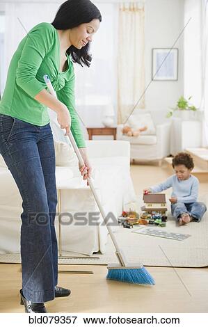 Stock Photo - Mixed race mother sweeping floor. Fotosearch