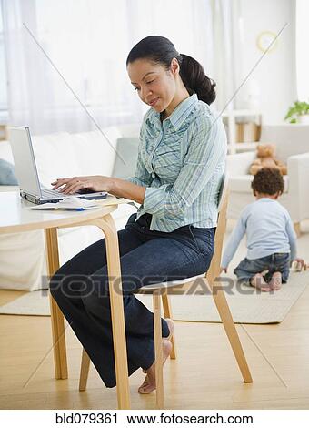 Mixed race mother typing on laptop View Large Photo Image Stock Image - Mixed race mother typing on laptop. Fotosearch