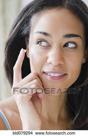 Picture - Mixed race woman applying lotion. Fotosearch