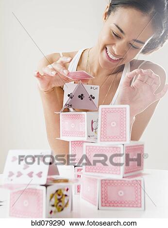 Stock Image - Mixed race woman building house of cards. Fotosearch