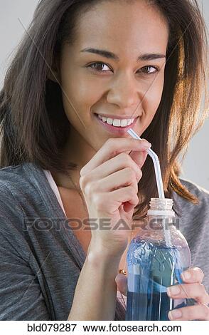 Stock Photo - Mixed race woman drinking soda through straw. Fotosearch
