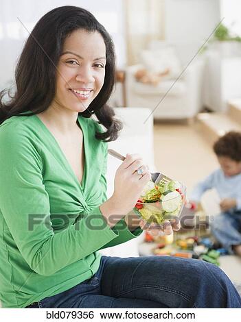 Stock Photograph - Mixed race woman eating salad. Fotosearch
