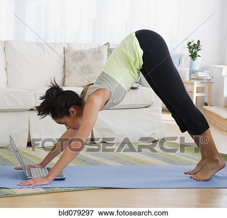 Stock Photo - Mixed race woman practicing yoga with laptop. Fotosearch