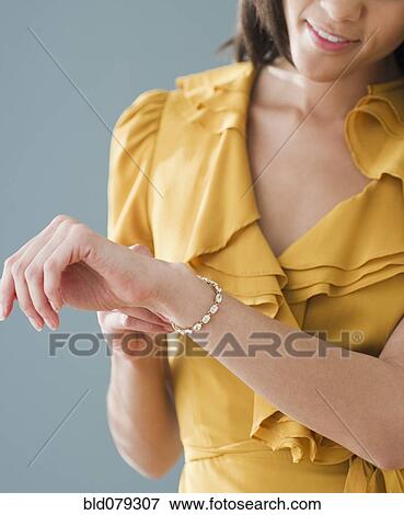 Stock Photo - Mixed race woman putting on bracelet. Fotosearch