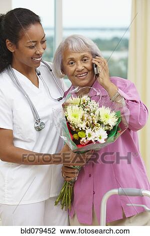 Nurse helping African American woman talking on cell phone View Large Photo Image Stock Image - Nurse helping African American woman talking on cell phone. Fotosearch