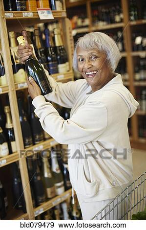 Stock Photo - Senior African American woman buying champagne. Fotosearch