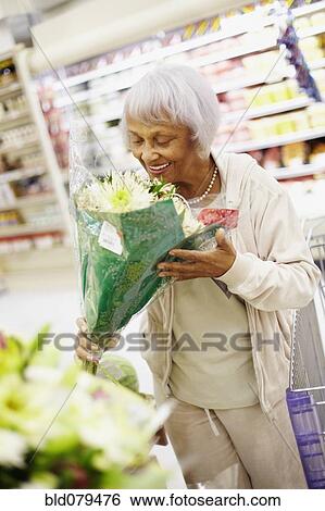 Stock Photograph - Senior African American woman in grocery store with bouquet of flowers. Fotosearch