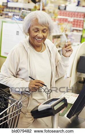 Senior African American woman paying with credit card in grocery store View Large Photo Image Stock Image - Senior African American woman paying with credit card in grocery store. Fotosearch