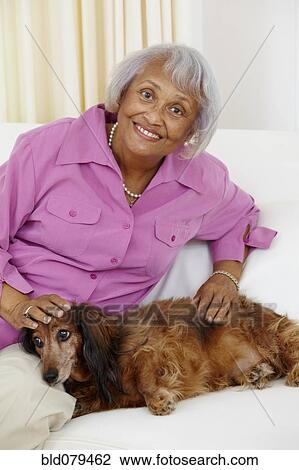 Stock Image - Senior African American woman petting dog. Fotosearch
