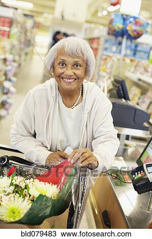 Stock Image - Senior African American woman shopping in grocery store. Fotosearch