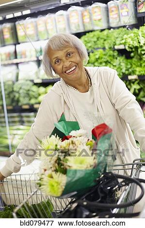 Stock Photo - Senior African American woman shopping in grocery store. Fotosearch