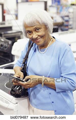 Senior African American woman text messaging on cell phone View Large Photo Image Stock Photo - Senior African American woman text messaging on cell phone. Fotosearch