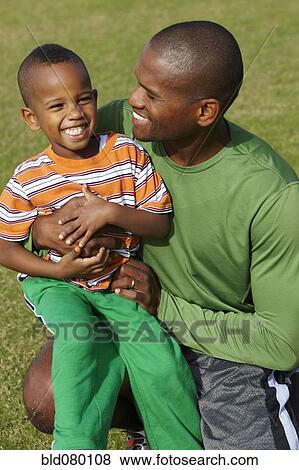 Stock Photo - African American father holding son on lap. Fotosearch